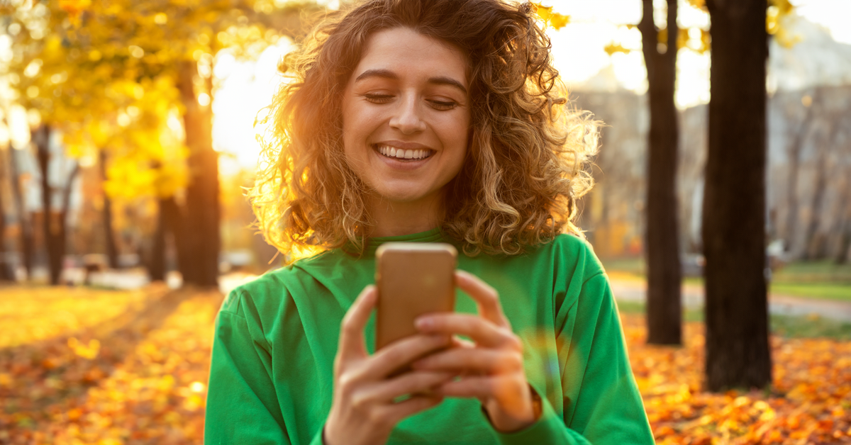 Active woman using phone outdoors in the fall